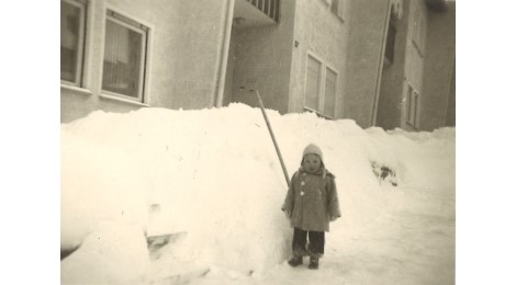 Kind vor einem Schneeberg vor der Haustür